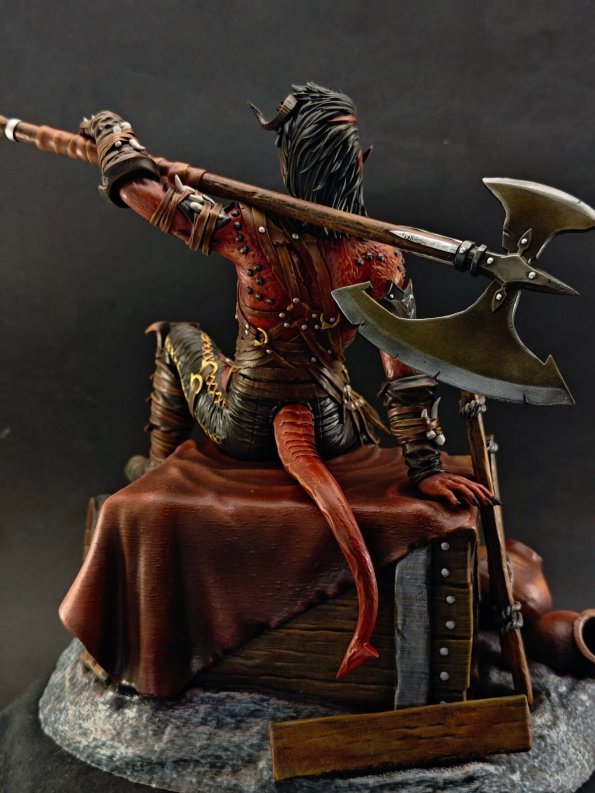 Back view of Karlach highlighting axe handle, cloak edge, and spine sculpt